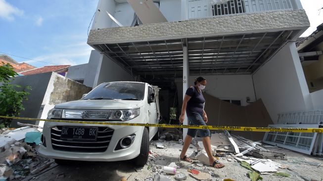 Warga melewati garis polisi saat mengamati kondisi bangunan rumah yang rusak akibat ledakan keras di kompleks Cluster Palm Puri Gading Loft B30, Kelurahan Jimbaran, Badung, Bali, Selasa (1/6/2021).  ANTARA FOTO/Nyoman Hendra Wibowo