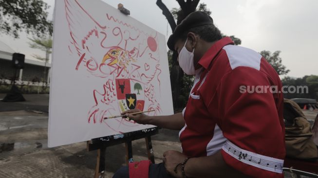 Seorang pelukis membuat lukisan saat Peringatan Hari Lahir Pancasila di Kompleks Gelora Bung Karno, Jakarta, Selasa (1/6/2021). [Suara.com/Angga Budhiyanto]