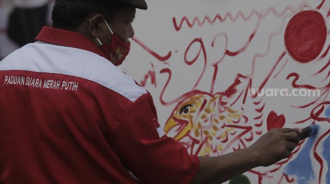 Seorang pelukis membuat lukisan saat Peringatan Hari Lahir Pancasila di Kompleks Gelora Bung Karno, Jakarta, Selasa (1/6/2021). [Suara.com/Angga Budhiyanto]