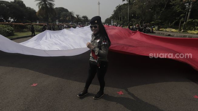 Sejumlah massa mengibarkan bendera merah putih raksasa di kawasan Patung Kuda Arjuna Wiwaha, Jakarta, Rabu (2/6/2021). [Suara.com/Angga Budhiyanto]