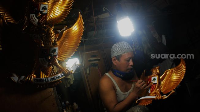 Perajin menyelesaikan pembuatan Patung Garuda di Jalan Bali Raya, Kalimalang, Jakarta Timur, Rabu (2/6/2021). [Suara.com/Dian Latifah]