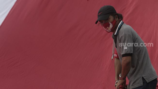 Massa merapikan kembali bendera merah putih raksasa usai mengibarkannya di kawasan Patung Kuda Arjuna Wiwaha, Jakarta, Rabu (2/6/2021). [Suara.com/Angga Budhiyanto]