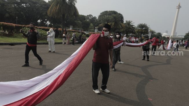 Sejumlah massa bersiap mengibarkan bendera merah putih raksasa di kawasan Patung Kuda Arjuna Wiwaha, Jakarta, Rabu (2/6/2021). [Suara.com/Angga Budhiyanto]