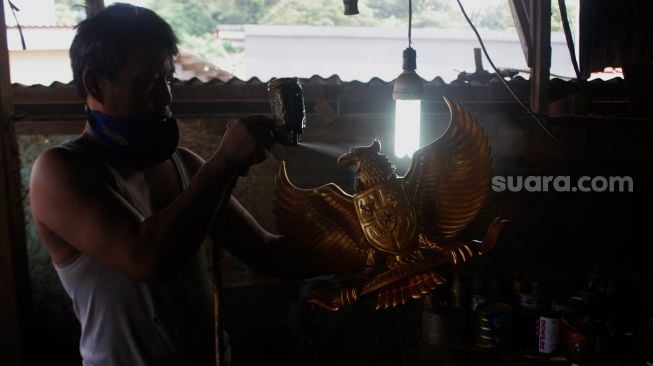 Perajin menyelesaikan pembuatan Patung Garuda di Jalan Bali Raya, Kalimalang, Jakarta Timur, Rabu (2/6/2021). [Suara.com/Dian Latifah]