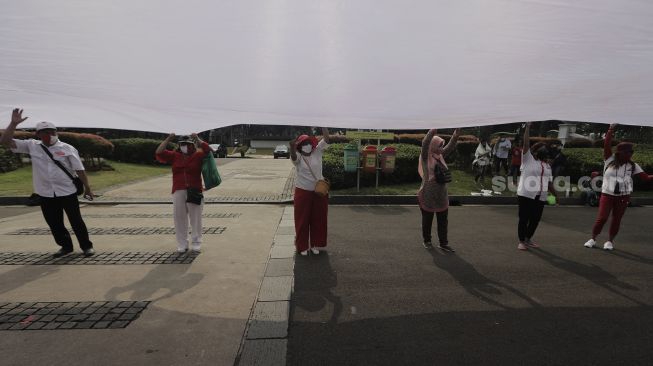 Sejumlah massa mengibarkan bendera merah putih raksasa di kawasan Patung Kuda Arjuna Wiwaha, Jakarta, Rabu (2/6/2021). [Suara.com/Angga Budhiyanto]