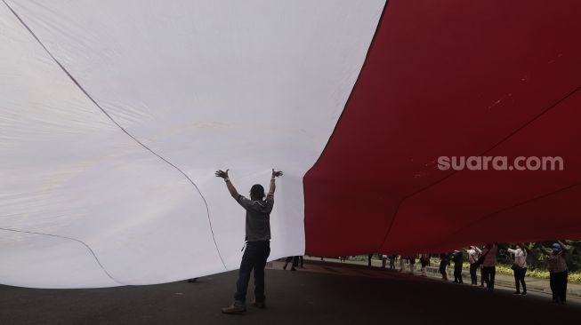 Sejumlah massa mengibarkan bendera merah putih raksasa di kawasan Patung Kuda Arjuna Wiwaha, Jakarta, Rabu (2/6/2021). [Suara.com/Angga Budhiyanto]