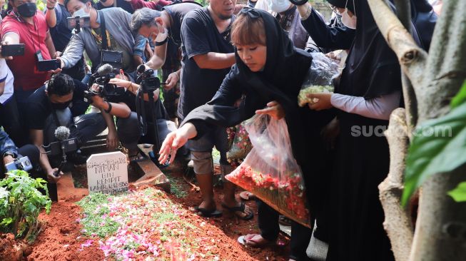 Komedian Mpok Alpa menebar bunga saat prosesi pemakaman sang Ayah di Tempat Pemakaman Khusus Keluarga, Jagakarsa, Jakarta Selatan, Kamis (3/6/2021). [Suara.com/Alfian Winanto]