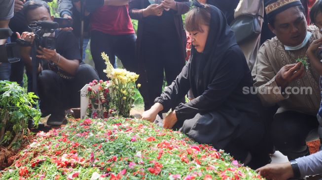 Komedian Mpok Alpa berdoa di atas pusara sang Ayah setelah dimakamkan di Tempat Pemakaman Khusus Keluarga, Jagakarsa, Jakarta Selatan, Kamis (3/6/2021). [Suara.com/Alfian Winanto]