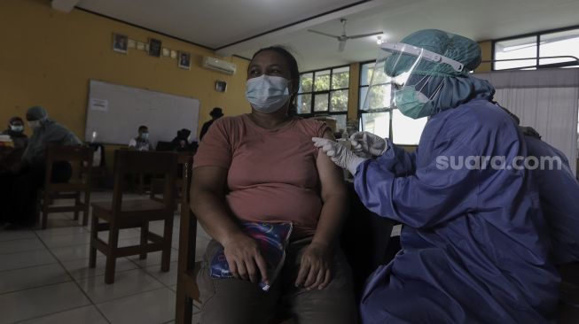 Vaksinator menyuntikan vaksin kepada warga di MTs As-Syafiiyah, Cilangkap, Jakarta, Kamis (3/6/2021). [Suara.com/Angga Budhiyanto]