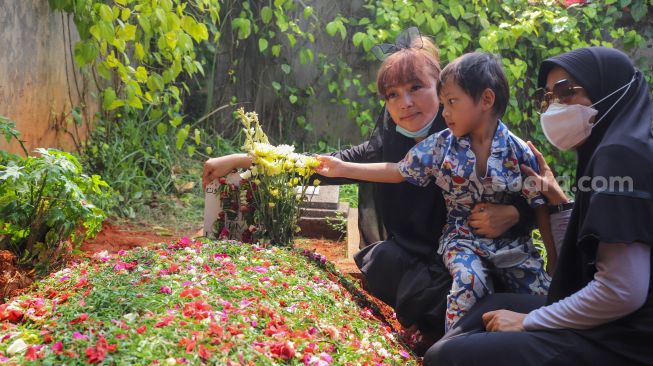 Komedian Mpok Alpa bersama anaknya berdoa di atas pusara sang Ayah setelah dimakamkan di Tempat Pemakaman Khusus Keluarga, Jagakarsa, Jakarta Selatan, Kamis (3/6/2021). [Suara.com/Alfian Winanto]