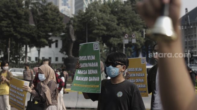 Sejumlah aktivis lingkungan hidup membawa poster saat melakukan aksi Jeda Untuk Iklim di kawasan Patung Kuda Arjuna Wiwaha, Jakarta, Jumat (4/6/2021). [Suara.com/Angga Budhiyanto]