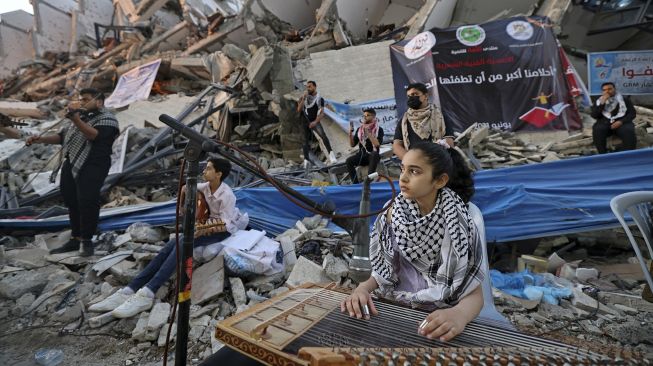 Musisi Palestina tampil di antara puing-puing reruntuhan Menara Hanadi di Kota Gaza, pada (2/6/2021). [MOHAMMED ABED / AFP]