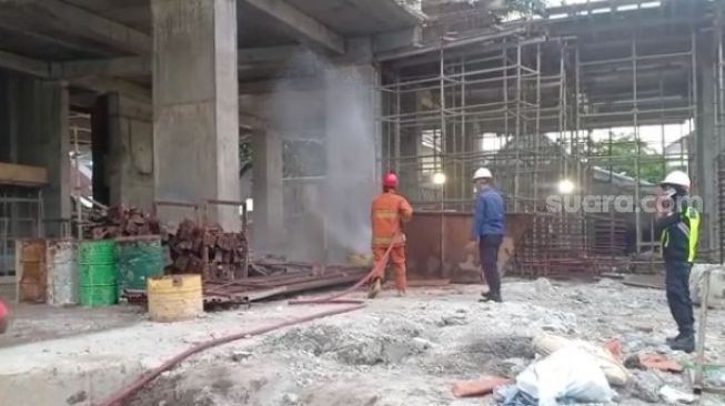 Petugas melakukan penyemprotan disinfektan di lokasi pembangunan Apartemen 31 Jalan Jenderal Sudirman Makassar, Jumat 4 Juni 2021 / [SuaraSulsel.id / Istimewa]