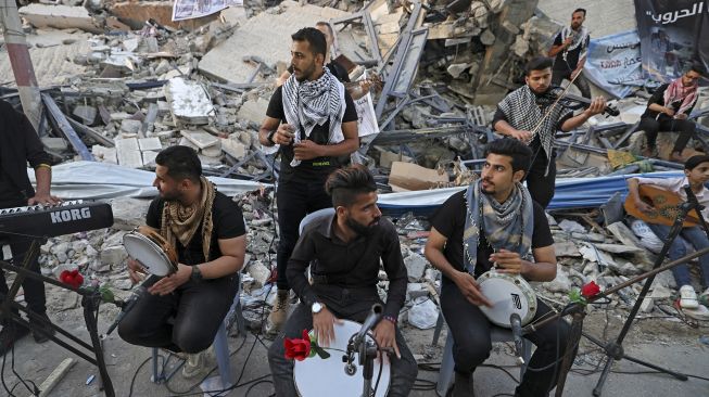 Musisi Palestina tampil di antara puing-puing reruntuhan Menara Hanadi di Kota Gaza, pada (2/6/2021). [MOHAMMED ABED / AFP]