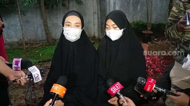 Aktris Oki Setiana Dewi (kiri) didampingi adiknya Shindy Putri menjawab pertanyaan dari wartawan usai prosesi pemakaman ayahnya, Sulyanto di Pondok Pesantren Daarul Qur'an, Cipondoh, Tangerang, Banten, Jumat (4/6/2021). [Suara.com/Rena Pangesti]