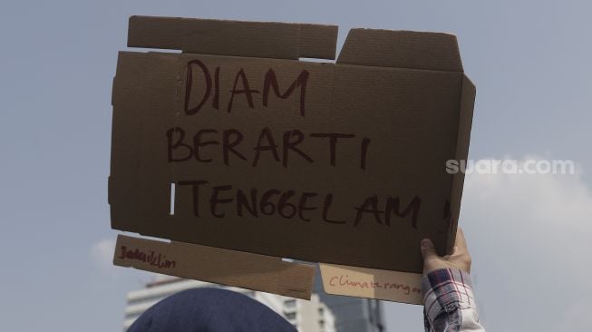 Aktivis lingkungan hidup membawa poster saat melakukan aksi Jeda Untuk Iklim di kawasan Patung Kuda Arjuna Wiwaha, Jakarta, Jumat (4/6/2021). [Suara.com/Angga Budhiyanto]