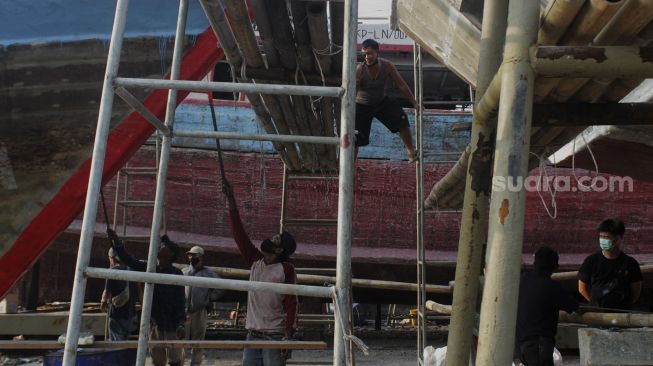 Sejumlah pekerja memperbaiki kapal di sebuah galangan kapal di kawasan Muara Angke, Jakarta Utara, Jumat (4/6/2021). [Suara.com/Dian Latifah] 