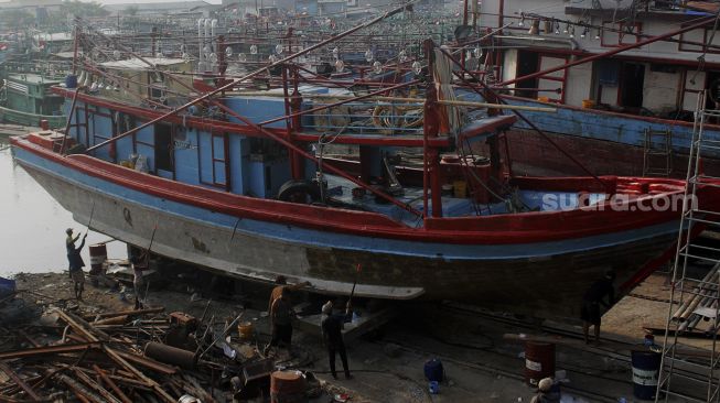 Sejumlah pekerja memperbaiki kapal di sebuah galangan kapal di kawasan Muara Angke, Jakarta Utara, Jumat (4/6/2021). [Suara.com/Dian Latifah]   