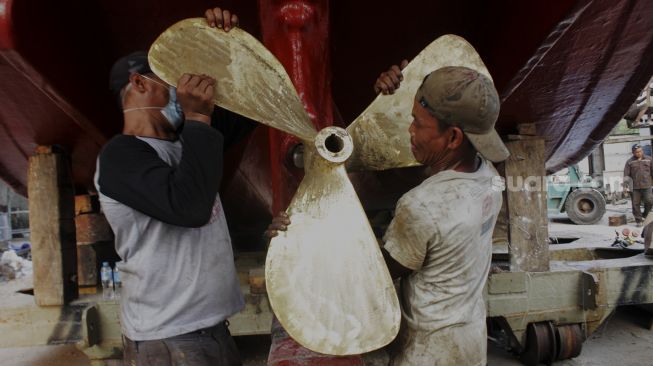 Pekerja memperbaiki baling-baling kapal di sebuah galangan kapal di kawasan Muara Angke, Jakarta Utara, Jumat (4/6/2021). [Suara.com/Dian Latifah] 