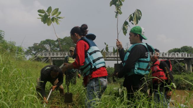 Sejumlah relawan menanam bibit pohon di bantaran kali Cikarang, Kabupaten Bekasi, Minggu (6/6/2021).  [Suara.com/Dian Latifah]