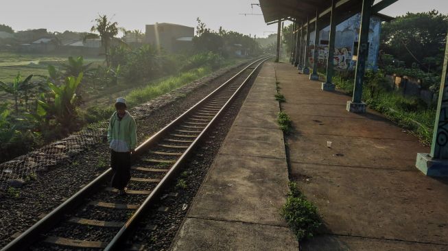 Warga berjalan di atas rel di Stasiun Pondok Rajeg yang tidak aktif di Cibinong, Bogor, Jawa Barat, Senin (7/6/2021).  ANTARA FOTO/Yulius Satria Wijaya
