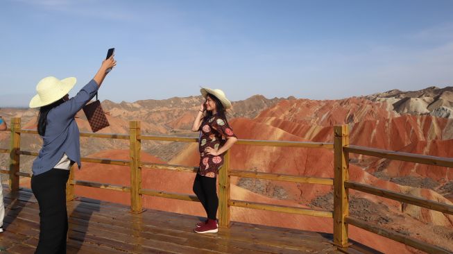 Wisatawan berpose dengan latar belakang panorama bukit warna-warni Taman Bumi Danxia di Kota Zhangye, Provinsi Gansu, China, Sabtu (5/6/2021). ANTARA FOTO/M. Irfan Ilmie