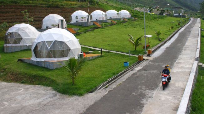 Wisatawan melintas di samping bangunan penginapan tahan gempa di Lembah Indah Resort, Malang, Jawa Timur, Selasa (8/6/2021). ANTARA FOTO/Ari Bowo Sucipto
