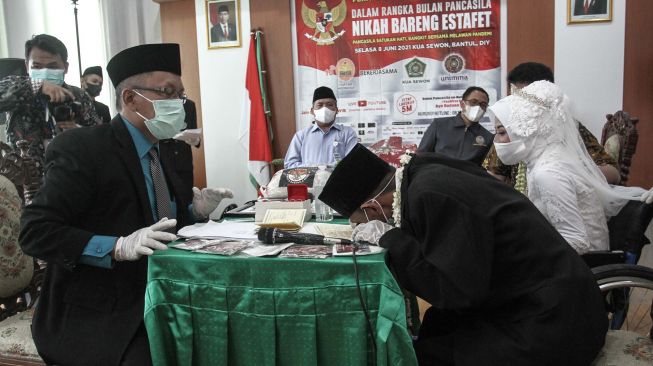 Pengantin menandatangani buku nikah saat acara Nikah Gratis di KUA Sewon, Bantul, DI Yogyakarta, Selasa (8/6/2021).  ANTARA FOTO/Hendra Nurdiyansyah