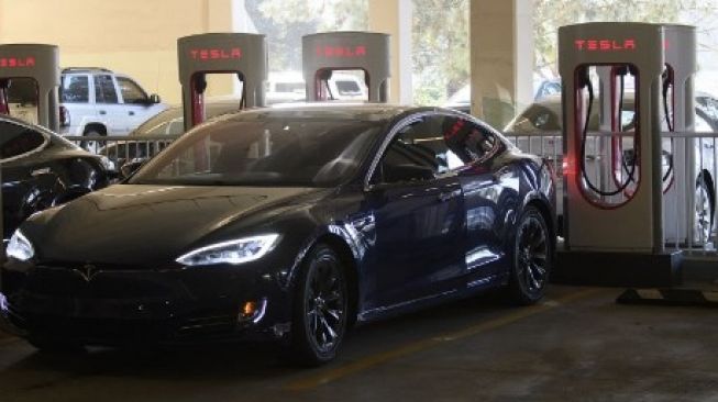 Mobil listrik produksi Tesla Incorporation tengah mengisi daya di stasiun supercharger di Redondo Beach, California, 2021. Sebagai ilustrasi produk dan infrastruktur Tesla [AFP/Patrick T. Fallon].