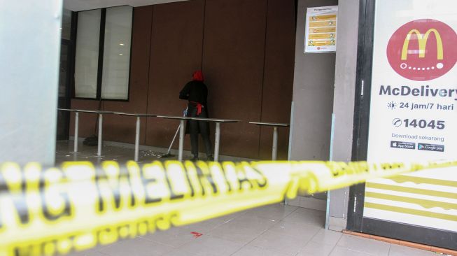 Pekerja gerai makanan siap saji Mc Donalds membersihkan halaman samping yang terpasang garis polisi di Kota Pekanbaru, Riau, Rabu (9/6/2021).  ANTARA FOTO/Rony Muharrman