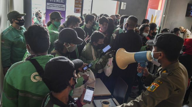 Petugas Satpol PP mengimbau pengemudi ojek daring untuk menerapkan protokol kesehatan di gerai McDonald’s Raden Saleh, Jakarta, Rabu (9/6/2021). ANTARA FOTO/Galih Pradipta