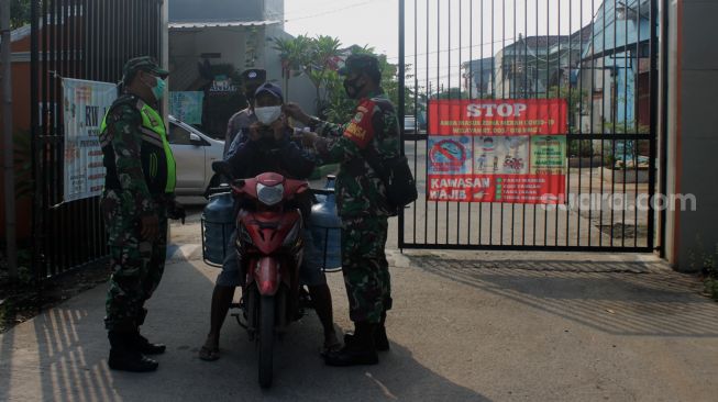 Petugas memeriksa warga yang melintas di Perumahan Villa Mutiara Gading 1, Desa Asih, Kecamatan Tarumajaya, Kabupaten Bekasi, Rabu (9/6/2021). [Suara.com/Dian Latifah]