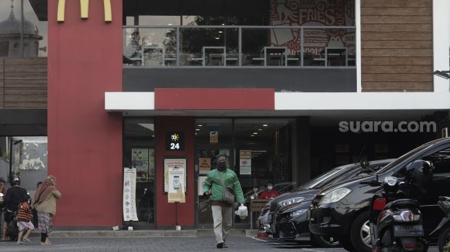 Seorang pengemudi ojek daring membawa pesanan pelanggan di gerai restoran cepat saji McDonald's Raden Saleh, Jakarta, Kamis (10/6/2021). [Suara.com/Angga Budhiyanto]