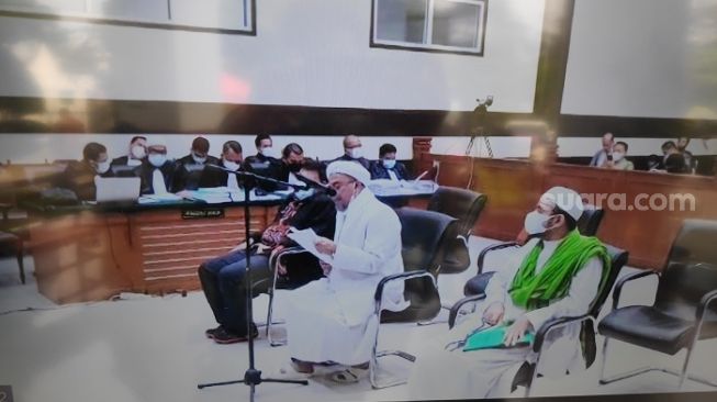 Habib Rizieq Shihab (tengah) saat membacakan pleidoi kasus tes swab di PN Jakarta Timur. (Suara.com/Bagaskara).