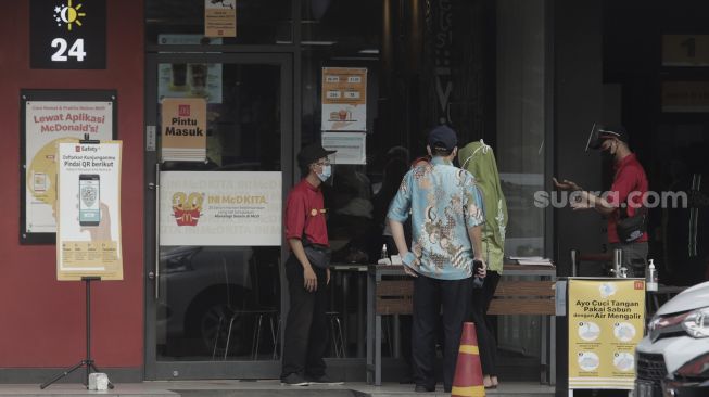 Petugas memeriksa kondisi kesehatan pengunjung sebelum memasuki gerai restoran cepat saji McDonald's Raden Saleh, Jakarta, Kamis (10/6/2021). [Suara.com/Angga Budhiyanto]