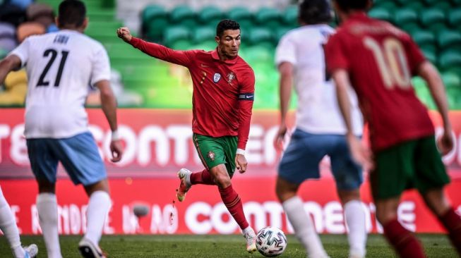 Penyarang Timnas Portugal, Cristiano Ronaldo (tengah) menendang bola dalam laga uji coba jelang Euro 2020 kontra Israel di Stadion Jose Alvalade, Kamis (10/6/2021) dini hari WIB. [PATRICIA DE MELO MOREIRA / AFP].