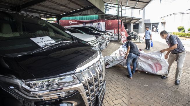 Petugas memasang penutup di dekat kendaraan sitaan milik tersangka kasus dugaan korupsi PT ASABRI (Persero) di Kantor Pusat PT ASABRI (Persero), Cawang, Jakarta, Sabtu (12/6/2021). [ANTARA FOTO/Aprillio Akbar]