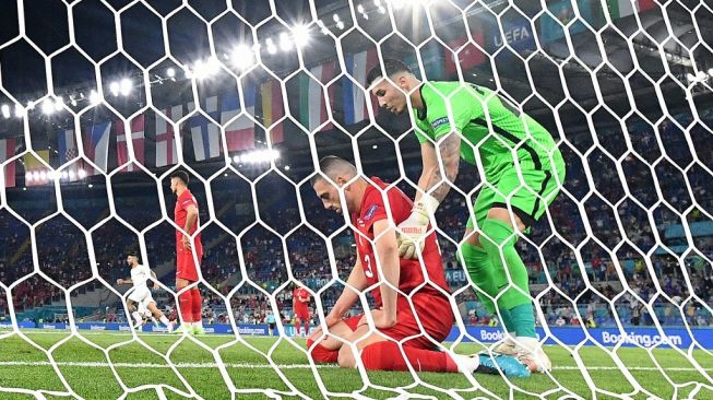 Bek Timnas Turki, Merih Demiral (bawah) tertunduk lesu usai mencetak gol bunuh diri pada laga Grup A Euro 2020 kontra Italia di Stadio Olimpico, Roma, Sabtu (12/6/2021) dini hari WIB. [Filippo MONTEFORTE / AFP]