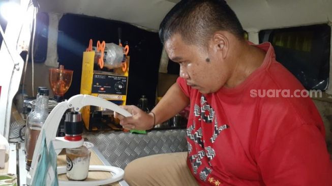 Rahmat Susanto tengah membuat satu cup Kopi Susu Inspirasi hasil racikannya di kedai Kito Rato. [SuaraJakarta.id/Wivy Hikmatullah]