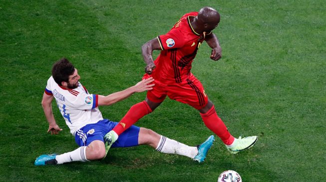 Pemain depan Belgia Romelu Lukaku (kanan) ditekel oleh bek Rusia Georgiy Dzhikiya selama pertandingan sepak bola Grup B EURO 2020 antara Belgia melawan Rusia di Stadion Saint Petersburg di Saint Petersburg, Rusia, Minggu (13/6). dinih hari WIB. ANTON VAGANOV / KOLAM RENANG / AFP