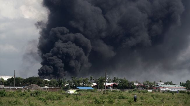 Asap hitam terlihat masih membumbung tinggi sesaat sebelum api berhasil dipadamkan, di Kilang Pertamina RU IV Cilacap, Jawa Tengah, Minggu (13/6/2021).  ANTARA FOTO/Idhad Zakaria