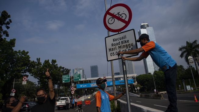 Petugas Dinas Perhubungan mencopot rambu bertuliskan �kecuali road bike� di sekitar Jalan Layang Non Tol (JLNT) Casablanca, Jakarta, Minggu (13/6/2021).  ANTARA FOTO/Sigid Kurniawan