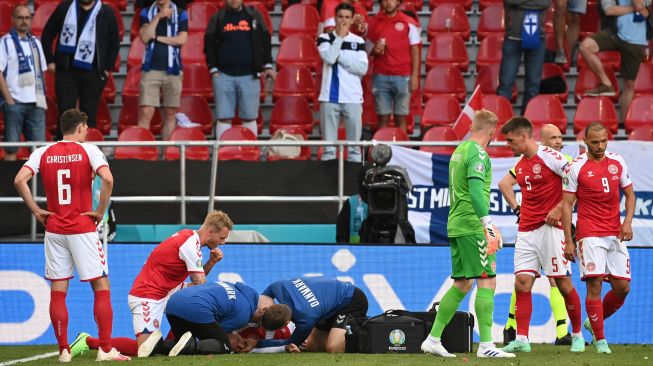 Pemain Denmark membantu gelandang Denmark Christian Eriksen setelah ia pingsan sebelum petugas medis tiba selama pertandingan sepak bola Grup BEURO 2020 antara Denmark melawan Finlandia di Stadion Parken di Kopenhagen, Sabtu (12/6).  Jonathan NACKSTRAND / AFP / POOL
