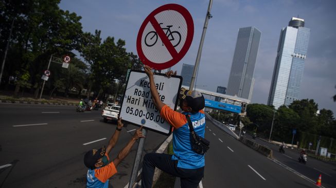 Petugas Dinas Perhubungan mencopot rambu bertuliskan �kecuali road bike� di sekitar Jalan Layang Non Tol (JLNT) Casablanca, Jakarta, Minggu (13/6/2021).  ANTARA FOTO/Sigid Kurniawan