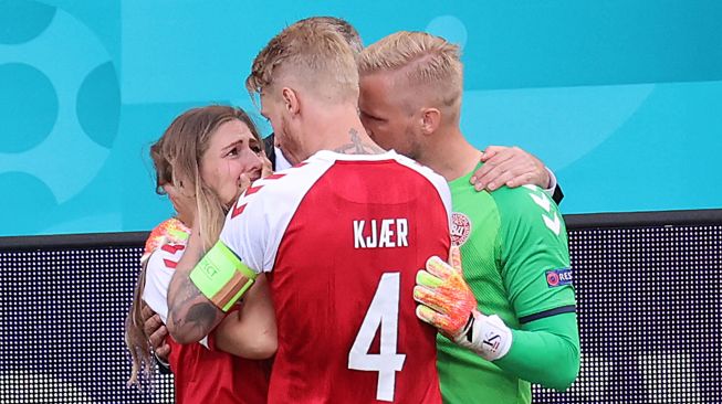 Kiper Denmark Kasper Schmeichel (kanan) dan bek Denmark Simon Kjaer (tengah) menghibur Sabrina Kvist Jensen, istri gelandang Denmark Christian Eriksen, setelah ia pingsan di lapangan selama pertandingan sepak bola Grup BEURO 2020 antara Denmark melawan Finlandia di Stadion Parken di Kopenhagen, Sabtu (12/6). WOLFGANG RATTAY / AFP / POOL