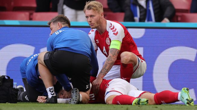 Pemain Denmark Simon Kjaer memeriksa gelandang Denmark Christian Eriksen ketika paramedis membawanya dengan tandu setelah ambruk  selama pertandingan sepak bola Grup BEURO 2020 antara Denmark melawan Finlandia di Stadion Parken di Kopenhagen, Sabtu (12/6). HANNAH MCKAY / POOL / AFP