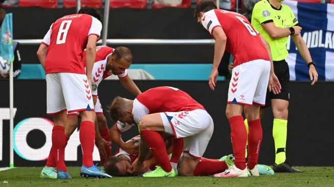 Pemain Denmark membantu gelandang Denmark Christian Eriksen setelah ia pingsan sebelum petugas medis tiba selama pertandingan sepak bola Grup BEURO 2020 antara Denmark melawan Finlandia di Stadion Parken di Kopenhagen, Sabtu (12/6).  Jonathan NACKSTRAND / AFP / POOL
