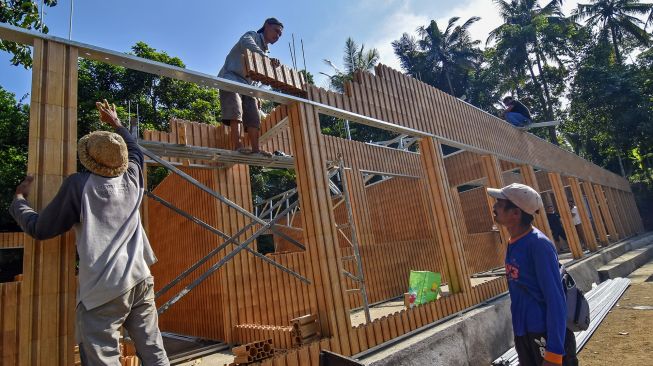 Sejumlah pekerja menyelesaikan pembangunan gedung Sekolah Dasar Negeri (SDN) 4 Medas Bentaur menggunakan bahan bata dari limbah plastik daur ulang di Dusun Medas Bentaur, Desa Taman Sari, Kecamatan Gunungsari, Lombok Barat, NTB, Senin (14/6/2021). ANTARA FOTO/Ahmad Subaidi