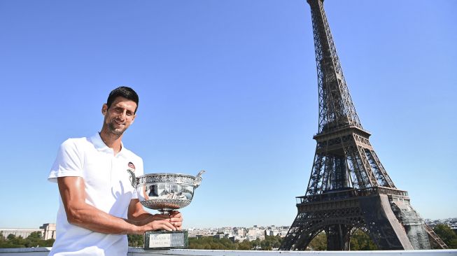 Petenis tunggal putera Serbia Novak Djokovic berpose dengan piala kemenangannya di depan Menara Eiffel, di Paris, Prancis, Senin (14/6 /2021).  Christophe ARCHAMBAULT / POOL / AFP