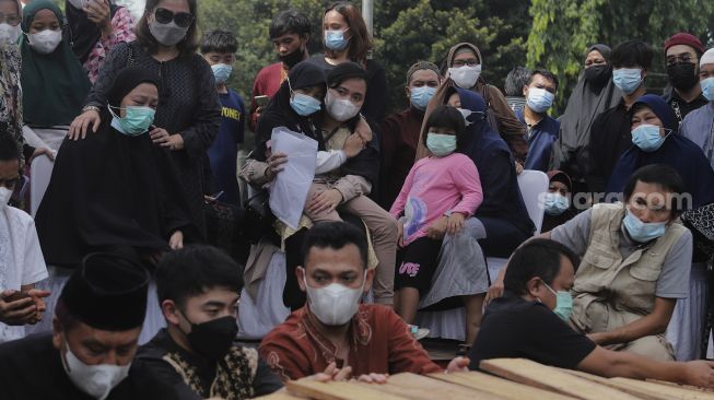 Keluarga menguburkan jenazah legenda bulutangkis Indonesia, Markis Kido di TPU Kebon Nanas, Cipinang, Jakarta, Selasa (15/6/2021). [Suara.com/Angga Budhiyanto]